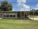 Inviting mobile home featuring a covered porch, verdant lawn, and clear, sunny skies at 5105 Wood St, Zephyrhills, FL 33542