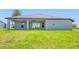 Spacious backyard with lush green grass, a covered patio, and a view of the surrounding neighborhood at 5317 Lydia Ct, Spring Hill, FL 34608