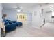 Bright living room featuring stylish blue sofa, light wood floors and view into a sunroom and kitchen at 5625 Atlantic N Ave, St Petersburg, FL 33703