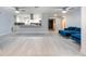 Bright living room featuring stylish blue sofa, light wood floors and view into the kitchen and entrance at 5625 Atlantic N Ave, St Petersburg, FL 33703