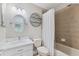 Bathroom with tiled shower/tub, white toilet, and vanity with round mirror and decorative shelf at 5823 Terncrest Dr, Lithia, FL 33547