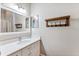 Bright bathroom featuring a white vanity with granite countertop, a framed mirror, and a wooden coat rack at 5823 Terncrest Dr, Lithia, FL 33547