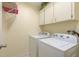 A clean laundry room features a white washer and dryer, upper cabinets and a wire shelf at 6340 Garland Ct, New Port Richey, FL 34652