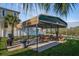 Outside picnic area with multiple tables under a metal awning next to a yard and walking trail at 6340 Garland Ct, New Port Richey, FL 34652
