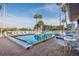 Community swimming pool with lounge chairs, poolside tables, and swaying palm trees at 6340 Garland Ct, New Port Richey, FL 34652