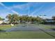 A full view of the tennis courts at the property with plenty of surrounding trees and lighting at 6340 Garland Ct, New Port Richey, FL 34652