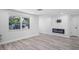Bright living room featuring modern fireplace, large window and sleek, gray, wood-look flooring at 6442 Sutherland Ave, New Port Richey, FL 34653