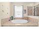 Luxury bathroom featuring a large soaking tub with a tile surround and a separate glass-enclosed shower at 6934 Duffy Ln, Tampa, FL 33616
