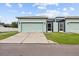 Exterior features a light-green facade with a two-car garage and a well-manicured lawn at 6934 Duffy Ln, Tampa, FL 33616