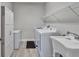 Well-lit laundry room with tile floors, storage cabinets, utility sink, and included washer and dryer at 7116 Estero Ct, Apollo Beach, FL 33572