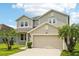 Inviting two-story home boasting a lush lawn, two palm trees, and a two-car garage at 7509 Tangle Bend Dr, Gibsonton, FL 33534