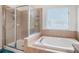This bright bathroom features a shower, a tub, and large window with lots of natural light at 7641 Armonk Ln, Wesley Chapel, FL 33545