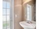 Bright bathroom featuring a pedestal sink, a large mirror, and a door to the exterior at 7641 Armonk Ln, Wesley Chapel, FL 33545
