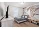 This bedroom features a decorative geometric accent wall, a cozy bed and bright natural light at 7641 Armonk Ln, Wesley Chapel, FL 33545