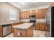Bright kitchen features laminate flooring, wood cabinetry, stainless appliances, and a center island at 7641 Armonk Ln, Wesley Chapel, FL 33545