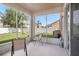 Enclosed porch with view of the green backyard, white fence and blue sky at 7641 Armonk Ln, Wesley Chapel, FL 33545