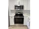 Close-up of a modern kitchen with stainless steel stove and microwave, white cabinets, and elegant countertops at 7703 Glenview Ln, Tampa, FL 33615