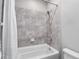 Bathroom featuring a shower-tub combo with a rainfall shower head and gray patterned tile at 8019 Marbella Creek Ave, Tampa, FL 33625