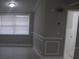 Bright living room showcasing wainscotting, neutral paint, and a large window for natural light at 8234 Ravencroft Dr, Tampa, FL 33615