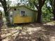 Side view of a small cottage with weathered exterior and bordered with foliage at 8617 Broad St, New Port Richey, FL 34654