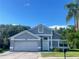 Charming one-story home featuring a two-car garage, well-maintained lawn, and a freshly painted gray exterior at 921 Linn Harbor Ct, Tarpon Springs, FL 34689