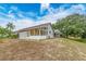 A sunroom on a single-story house features a wall of windows in a spacious backyard and blue skies at 921 Linn Harbor Ct, Tarpon Springs, FL 34689