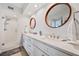 Bright bathroom with double sinks, white cabinetry, wood-look flooring, and a glass enclosed shower at 960 Starkey Rd # 7503, Largo, FL 33771