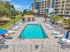 Community pool with lounge chairs, umbrellas, and tropical landscaping at condominium complex at 960 Starkey Rd # 7503, Largo, FL 33771
