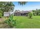 Backyard view showcasing lush grass, screened in pool, and tropical landscaping at 10113 Bell Creek Dr, Riverview, FL 33569