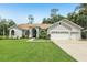 Charming one-story home with manicured lawn, an arched entryway, and a three-car garage with a light gray exterior at 10113 Bell Creek Dr, Riverview, FL 33569