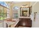 A well lit main bathroom featuring dual vanities, soaking tub, and walk in shower at 10113 Bell Creek Dr, Riverview, FL 33569
