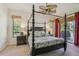Bedroom with four-poster bed, ceiling fan, and views of the lush backyard at 10113 Bell Creek Dr, Riverview, FL 33569