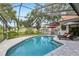 Sparkling pool surrounded by stone patio, screened enclosure, lounge chairs, and manicured landscaping at 10113 Bell Creek Dr, Riverview, FL 33569