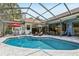 Inviting outdoor pool with a screened enclosure, complemented by poolside furniture and lush landscaping at 10113 Bell Creek Dr, Riverview, FL 33569
