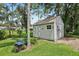 Side view of shed with gray walls, green grass and mature trees at 10113 Bell Creek Dr, Riverview, FL 33569