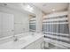 Bright bathroom features double vanity with white countertop and grey and white striped shower curtain at 10580 Gliding Eagle Way, Land O Lakes, FL 34638