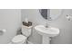 Cozy bathroom with a pedestal sink, toilet, decorative mirror, and a neutral color palette at 10580 Gliding Eagle Way, Land O Lakes, FL 34638