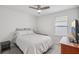 Neutral bedroom with a gray bed set, a window for natural light, a ceiling fan, and simple wooden furniture at 10580 Gliding Eagle Way, Land O Lakes, FL 34638