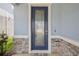 Stylish front door with glass panel, complemented by stone accents and neutral wall color at 10580 Gliding Eagle Way, Land O Lakes, FL 34638