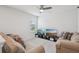 Living room featuring two comfortable sofas with decorative pillows, a ceiling fan, and a TV stand at 10580 Gliding Eagle Way, Land O Lakes, FL 34638