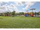 A view of the community playground with colorful equipment, covered picnic area, and green lawns at 10580 Gliding Eagle Way, Land O Lakes, FL 34638
