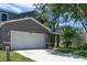 View of the home's exterior features a two-car garage, manicured lawn, and well-kept landscaping at 10605 Marsanne Pl, Riverview, FL 33578