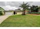 Charming yellow home featuring a well-manicured lawn, stone accents, and a spacious two-car garage at 1117 S Florida Ave, Tarpon Springs, FL 34689