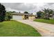Charming one-story home with a well-manicured lawn, a beautiful curved driveway, and mature palm trees at 1117 S Florida Ave, Tarpon Springs, FL 34689