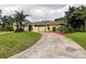 Charming one-story home with a well-manicured lawn, a beautiful curved driveway, and mature palm trees at 1117 S Florida Ave, Tarpon Springs, FL 34689