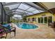 Screened-in pool area with a pool, travertine tile floor, and an adjoining home with sliding glass doors at 1117 S Florida Ave, Tarpon Springs, FL 34689