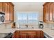 Cozy kitchen with wood cabinets, stainless steel appliances, and a window overlooking the water at 1290 Gulf Blvd # 702, Clearwater Beach, FL 33767