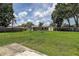 Wide shot of a well-maintained backyard with green grass and a few small trees, under a cloudy sky at 14047 Briardale Ln, Tampa, FL 33618