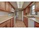 Galley style kitchen showcases wood cabinetry, tile flooring, stainless steel appliances, and neutral countertops at 14047 Briardale Ln, Tampa, FL 33618