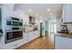 Modern kitchen featuring stainless steel appliances, white cabinets, and wood floors, offering a sleek design at 14534 Yacht Club Blvd, Seminole, FL 33776